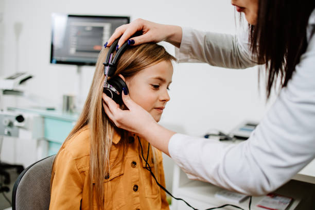 Audiologist doing impedance audiometry or diagnosis of hearing impairment. An beautiful teenage girl getting an auditory test at a hearing clinic. Healthcare and medicine concept.